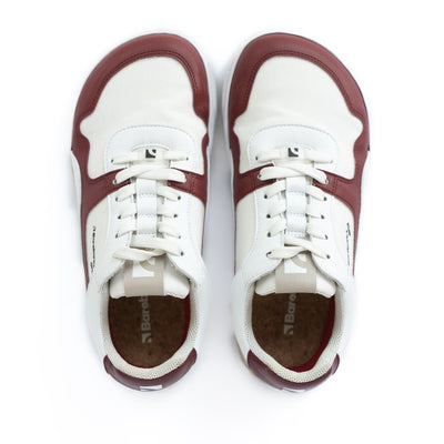 Barebarics Zing sneakers made with a leather upper and a rubber sole. The sneakers are white with burgundy accents around the front and side, and a tan accent over the heel. There are perforated spots on the top of the toe box and barebarics branding on the tongue and side. Both sneakers are shown side by side from above, on a white background. #color_burgundy-anya-exclusive