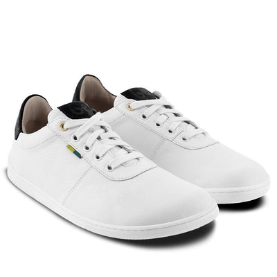 A photo of Be Lenka Royale sneakers made with a leather upper and a rubber sole. The sneakers are a white color and the area around the heel is black, they have small yellow and blue tag on the side. Both sneakers are shown beside each other angled from the right side against a white background. #color_white-black