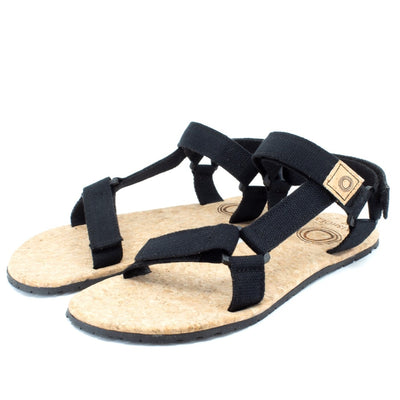 Black Mukishoes Solstice. Sandals have thicker cotton adjustable straps going over the toes and surrounding the ankle with straps connecting the toe and ankle straps. Footbed is quark and sole is a thin black rubber. Both shoes are shown here diagonally facing to the left against a white background. #color_black