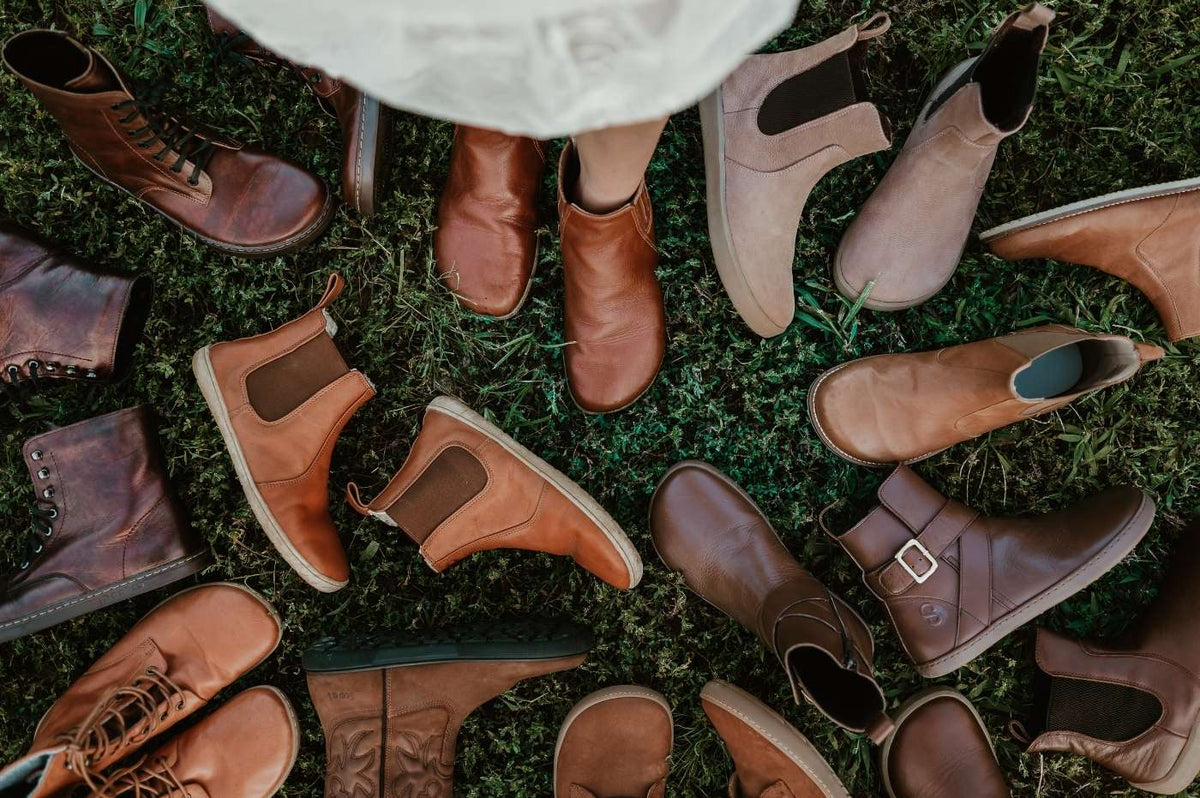 Collection of brown boots on grass.