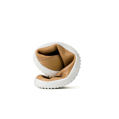 Beige colored vegan sneakers shown from a curled up view on a white background. To show shoes flexibility. #color_beige