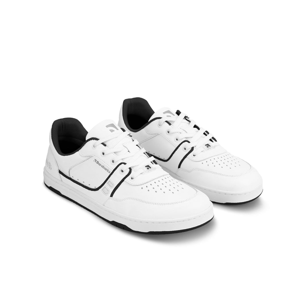 A photo Barebarics Arise chunky leather sneaker in white with black and white soles and white laces. Shoes are perforated on the sides and toe box and have green detailing on the soles, both sides of the shoe, and the lining. Both shoes are shown facing diagonally right against a white background. #color_white-black