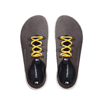 Photo 1 - A photo Barebarics Bronx chunky leather sneaker in midnight black with white soles and yellow laces. Shoes are surrounded by suede with a black pull-on style tongue and ankle opening. Laces are attached by metal boot eyelets. Right shoe is shown from the right side against a white background. Photo 2 - Both shoes are shown from the top down against a white background. #color_midnight-black