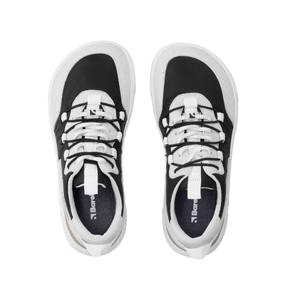 Photo 1 - A photo of Barebarics Revive sneakers in light grey & black with white soles. The sneakers are made of a black tent-like fabric with light grey suede-like material bordering around the toe box, laces, ankle, and heel. Decorative thin elastic laces lay overtop of white fabric laces. Right sneaker is shown here from the right side against a white background., Photo 2 - Both shoes are shown from the top down against a white background. #color_light-grey-black