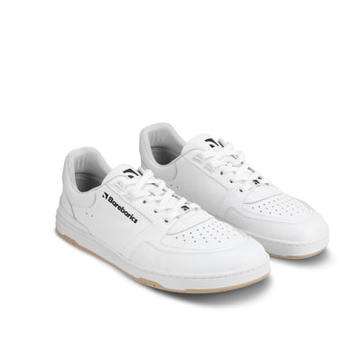A photo of all white Barebarics Wave classic leath sneakers. Toe box is perforated, the sole is white with tan thread, barebarics brand name is written on the side. Both sneakers are shown here diagonally from the front right against a white background. #color_all-white