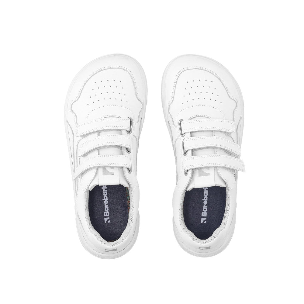 Photo 1 - A photo of white Barebarics Zing leather sneakers. Shoes have perforated spots on the top of the toe box, have barebarics branding on the tongue and side, and a velcro straps instead of laces. Left sneaker is shown facing right with the right shoe heel leaning on the left shoe against a white background. Photo 2 - Both shoes are shown from above against a white background. #color_all-white