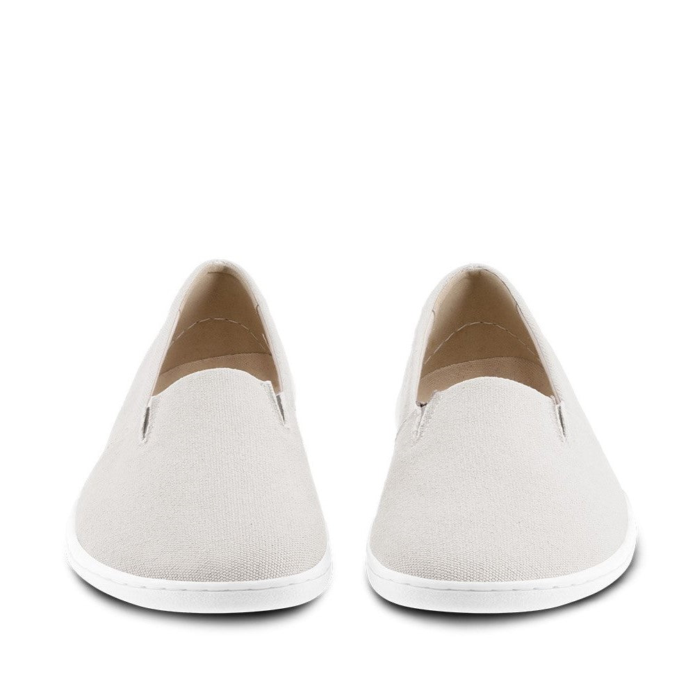 A photo of the Be Lenka Bali canvas slip on, the slip ons are a beige color with a yellow and green tag on the side. Both shoes are shown sitting beside each other facing towards the front against a white background. #color_beige