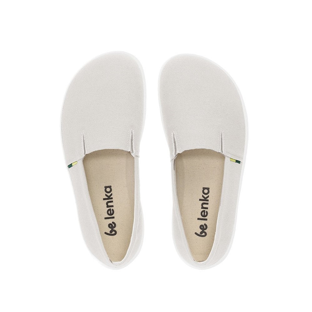 A photo of the Be Lenka Bali canvas slip on, the slip ons are a beige color with a yellow and green tag on the side. Both shoes are shoe beside each other front above facing upright against a white background. #color_beige