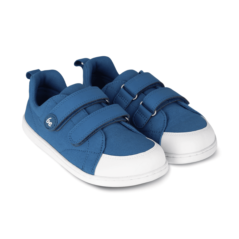 Blue canvas Be Lenka Canvi sneakers with  two velcro straps, white faux suede toe caps, white and teal rubber soles, and a pull tab at the heel. Both shoes are shown facing diagonally left against a white background. #color_blue