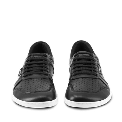 A photo of Belenka Champ sneakers made from leather and white rubber soles. The sneakers are black in color with perforation on the toe box and detail stitching. Both shoes are shown beside each other from the front against a white background. #color_black-white
