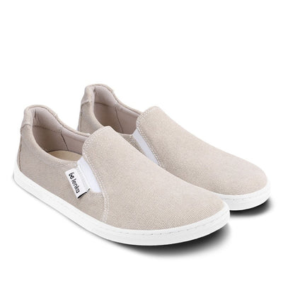 A photo of a sand canvas slip-on sneaker with white elastic on the sides, and a white sole. Both sneakers are shown beside each other angled to the right against a white background. #color_sand-canvas