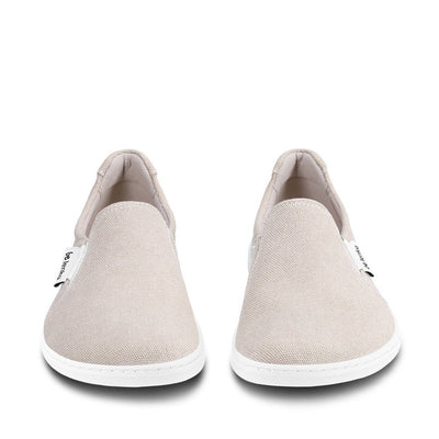 A photo of a sand canvas slip-on sneaker with white elastic on the sides, and a white sole. Both sneakers are shown beside each other from the front against a white background. #color_sand-canvas