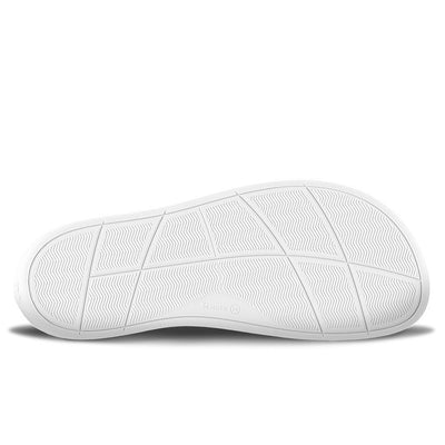 A photo of a sand canvas slip-on sneaker with white elastic on the sides, and a white sole. The right shoe is shown lying on its side to show the sole against a white background. #color_sand-canvas