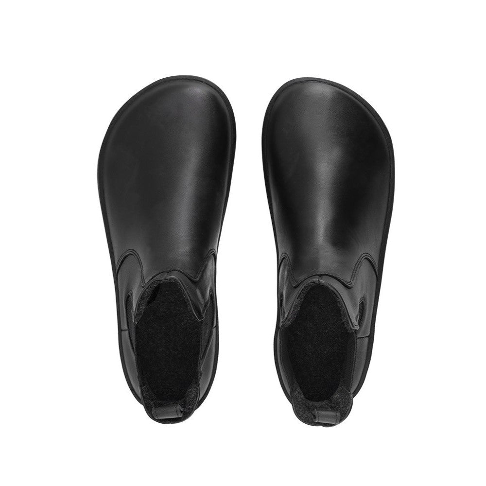 A photo of Belenka Entice Neo boots made from smooth leather and black rubber soles. The boots are black in color with elastic panels on the sides and pull on loops. Both shoes are shown from the top down against a white background. #color_black