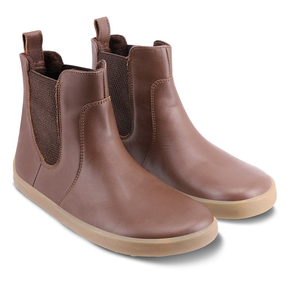 A photo of Belenka Entice Neo boots made from smooth leather and tan rubber soles. The boots are brown in color with dark brown elastic panels on the sides and pull on loops. Both shoes are shown beside each other from the front angled slightly to the right against a white background. #color_dark-brown