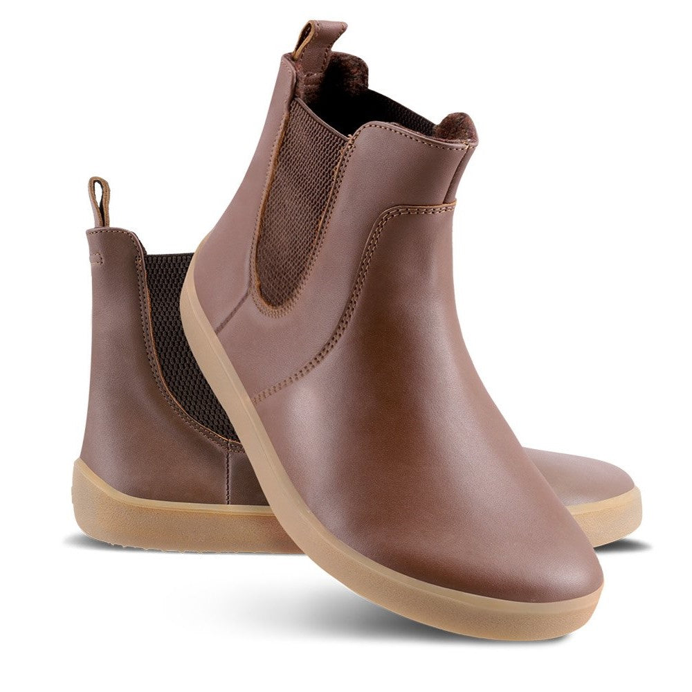 A photo of Belenka Entice Neo boots made from smooth leather and tan rubber soles. The boots are brown in color with dark brown elastic panels on the sides and pull on loops. Both shoes are shown the left shoe is sitting behind the right shoe, the right shoes heel is leaning on the left shoe and is facing downward against a white background. #color_dark-brown