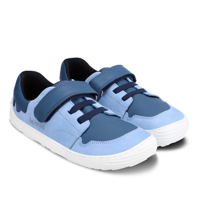 A photo of blue Be Lenka Gelato kids leather sneakers with white rubber soles. Shoes are light blue with dark blue accent color blocks on the tongue, toe box, single top velcro closure, two elastic laces below that, and a "dripping" ice cream color block on the heel. Both shoes are facing diagonally right against a white background. #color_blue
