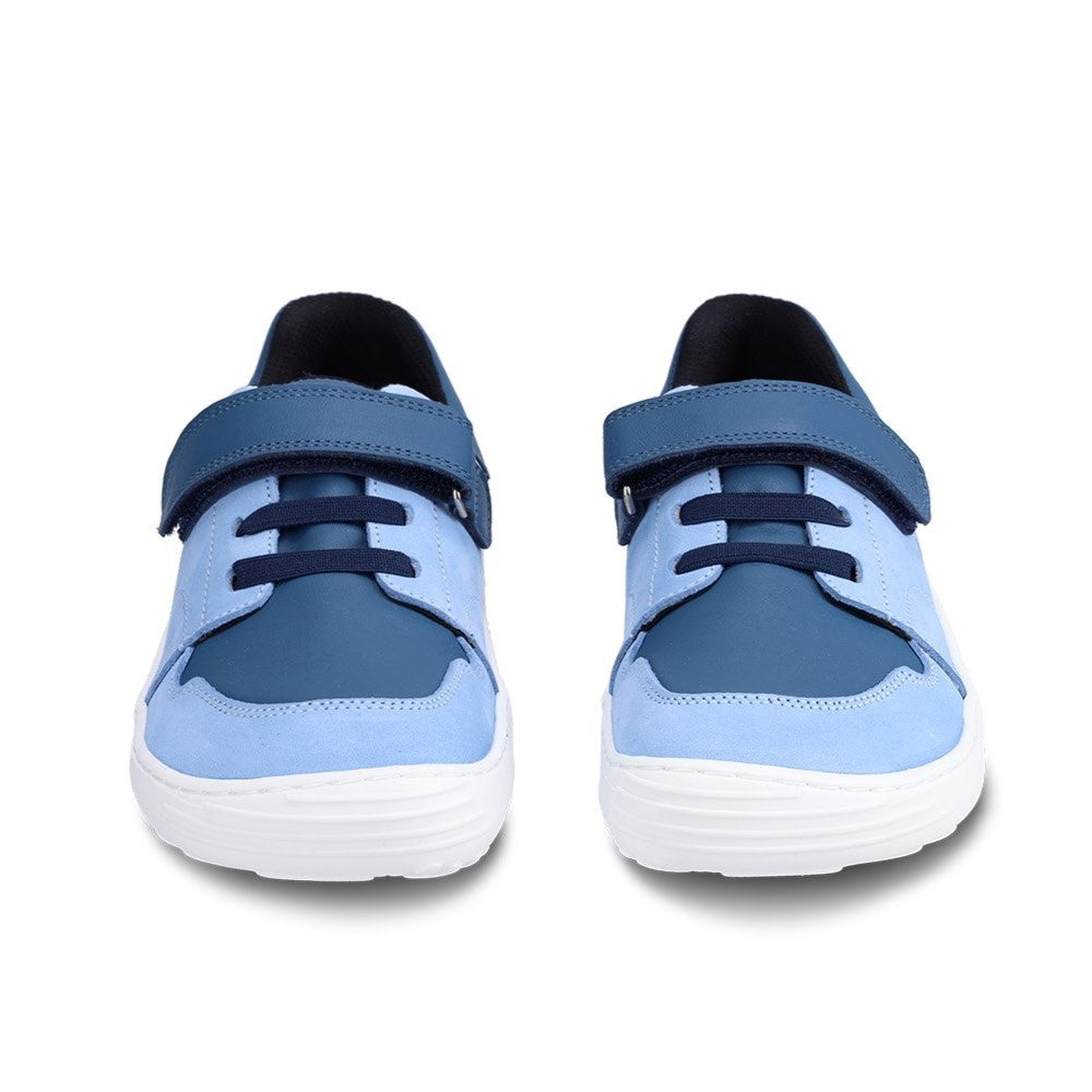 A photo of blue Be Lenka Gelato kids leather sneakers with white rubber soles. Shoes are light blue with dark blue accent color blocks on the tongue, toe box, single top velcro closure, two elastic laces below that, and a "dripping" ice cream color block on the heel. Both shoes are shown from the front against a white background. #color_blue