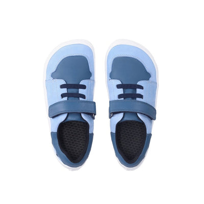 A photo of blue Be Lenka Gelato kids leather sneakers with white rubber soles. Shoes are light blue with dark blue accent color blocks on the tongue, toe box, single top velcro closure, two elastic laces below that, and a "dripping" ice cream color block on the heel. Both shoes are shown from above against a white background. #color_blue