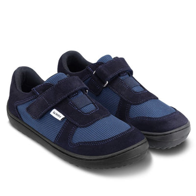 Photo 1 - A photo of Be Lenka Joy kids play shoes in dark blue and black. They are made of dark blue mesh and black suede in a classic sneaker design. A velcro strap at the top of the tongue and elastic band just below are in place of laces. Both shoes are shown diagonally from the front right against a white background. Photo 2 - Both shoes are shown from the top down against a white background. #color_dark-blue-black