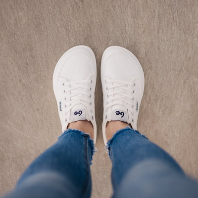 All White Be Lenka Rebound sneakers with white laces, microfiber toe guards, heel accents, and rubber soles. Both shoes are shown from above on feet standing on cement. #color_all-white