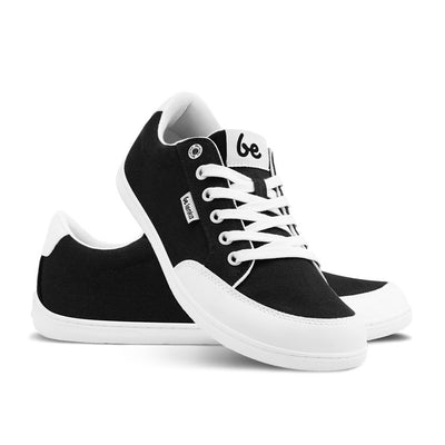 Black Be Lenka Rebound sneakers with white laces, microfiber toe guards, heel accents, and rubber soles. Left shoe is facing right with the right shoe heel resting on it facing diagonally right against a white background. #color_black-white