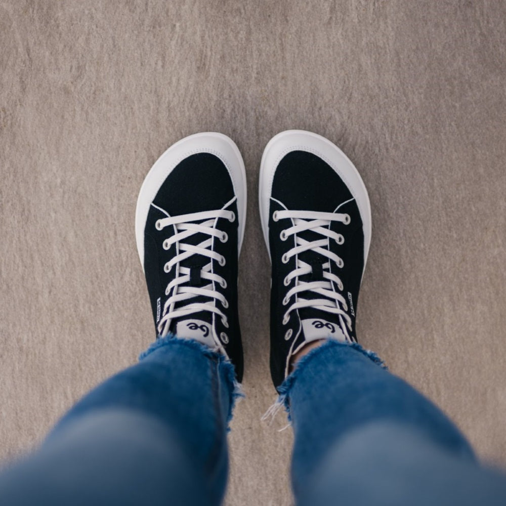 Black Be Lenka Rebound High Top sneakers with white laces, microfiber toe guards, heel accents, and rubber soles. Both shoes are shown from above on feet standing on cement. #color_black-white