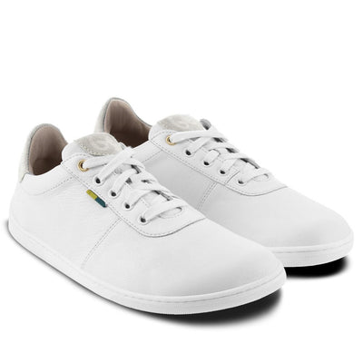 A photo of Be Lenka Royale sneakers made with a leather upper and a rubber sole. The sneakers are a white color and the area around the heel is beige, they have small yellow and blue tag on the side. Both sneakers are shown beside each other angled from the right side against a white background. #color_white-beige