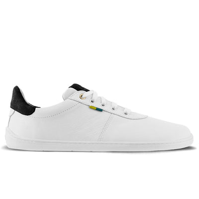 A photo of Be Lenka Royale sneakers made with a leather upper and a rubber sole. The sneakers are a white color and the area around the heel is black, they have small yellow and blue tag on the side. The right sneaker is shown from the side against a white background. #color_white-black