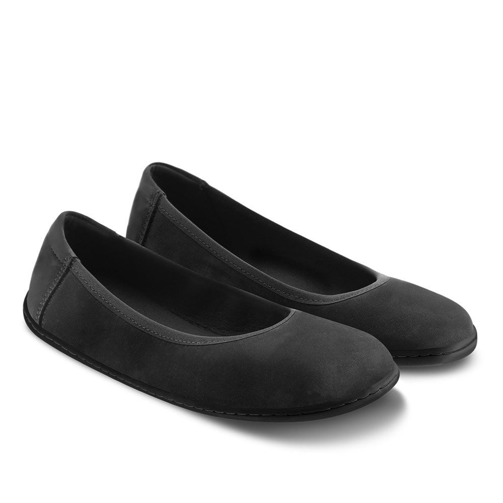 A photo of the Be Lenka Sophie flats made from a leather upper and a microfiber interior. The flats are black in color with black rubber soles and are a simple ballerina flat design. Both shoes are shown together with toes angled down toward the right on a white background. #color_matte-black