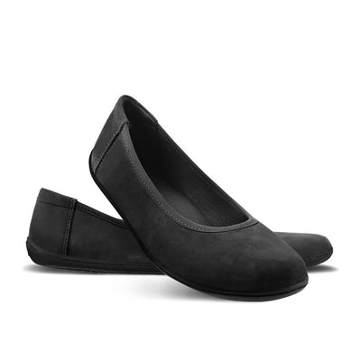 A photo of the Be Lenka Sophie flats made from a leather upper and a microfiber interior. The flats are black in color with black rubber soles and are a simple ballerina flat design. The right shoe is shown with its heel propped on the left shoe on a white background. #color_matte-black