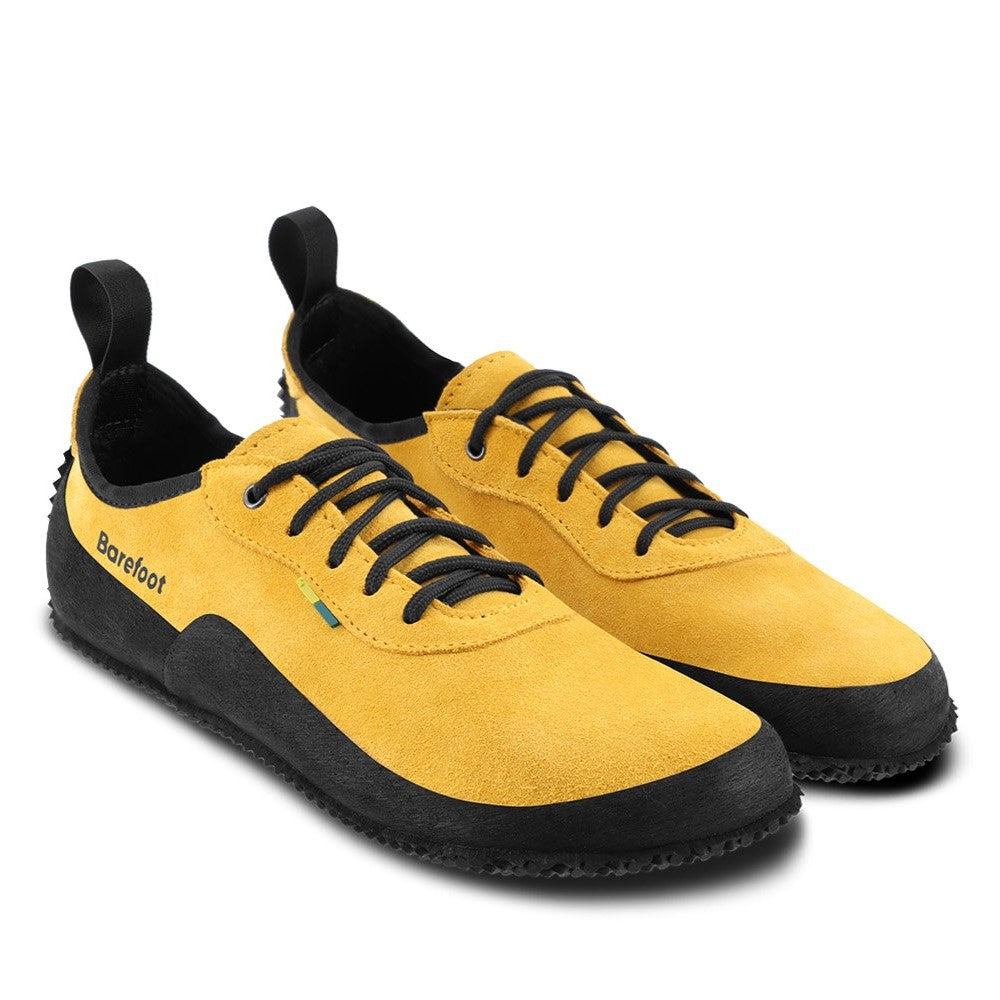 A photo of a hiking sneaker with a long heel pull on tab front angled slightly to the right side. The sneakers are mustard in color with black above the sole and bump rubber thread against a white background. #color_mustard