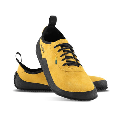A photo of a hiking sneaker with a long heel pull on tab. The right sneaker’s heel rests on the side of the left sneaker which is behind it. The sneakers are mustard in color with black above the sole and bump rubber thread against a white background. #color_mustard