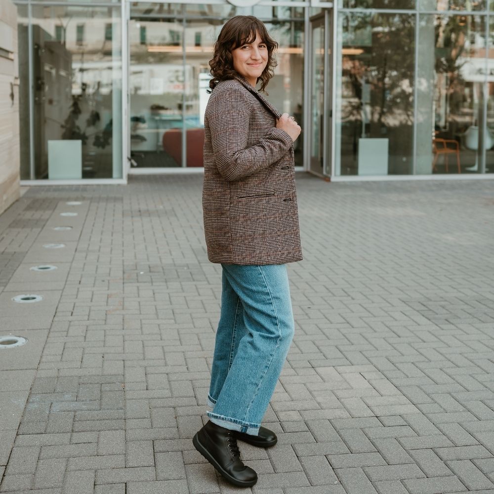 All black smoother leather Be Lenka Winter 3.0 lace up, wool lined boots.  Both boots are shown facing right on a light-skinned woman  with short/curly/brown hair wearing loose/cropped/light-wash jeans, and a brown plaid blazer standing a grey brick pathway in an urban setting. #color_black-smooth-leather