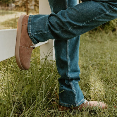 Walnut brown nubuck leather Be Lenka Winter 3.0 lace up, wool lined boots with tan rubber soles. Both boots are shown facing right on a man wearing a loose/medium-wash jeans standing in grass leaning against a white fence in a farm setting. #color_walnut-brown-nubuck