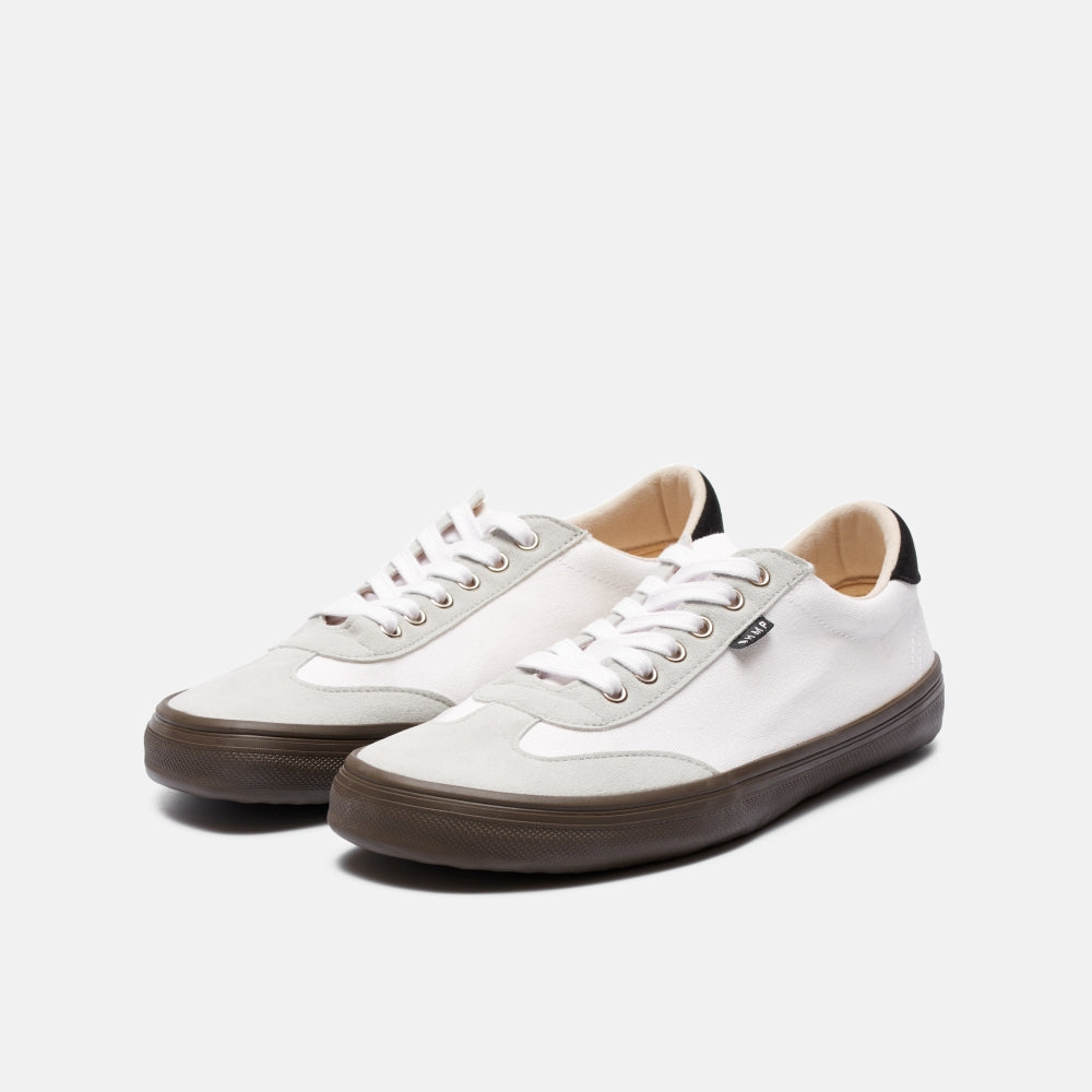 A photo of the Bohempia Felix vegan sneakers made from hemp canvas. The sneakers are white in color with a light grey vegan suede toe cap and a black heel detail, with a dark gum sole and white laces. Both shoes are shown diagonally from the front right on a white background. #color_white-dark-gum