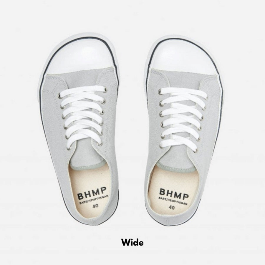 A photo of Bohempia Herlik canvas sneakers made from canvas and rubber soles. The sneakers are light grey with a white toe cap and a black outline around the white rubber soles. Both sneakers are shown from above on a white background with the word “wide” written under the sneakers. #color_light-grey-white