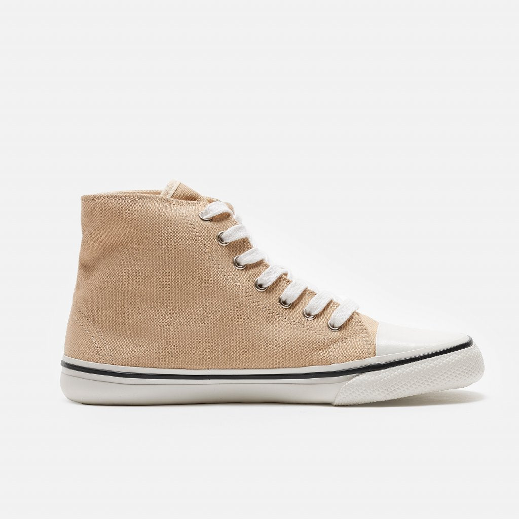 A photo of Bohempia Orik canvas high tops made from canvas and rubber soles. The sneakers are a tan color with a white toe cap and a black outline around the white rubber soles. The left sneaker is shown from the right side against a white background. #color_tan-white