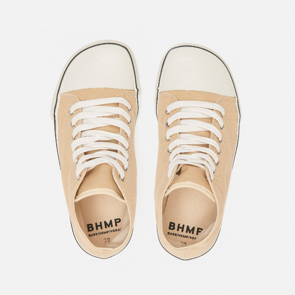 A photo of Bohempia Orik canvas high tops made from canvas and rubber soles. The sneakers are a tan color with a white toe cap and a black outline around the white rubber soles. Both sneakers are shown from the top down against a white background. #color_tan-white
