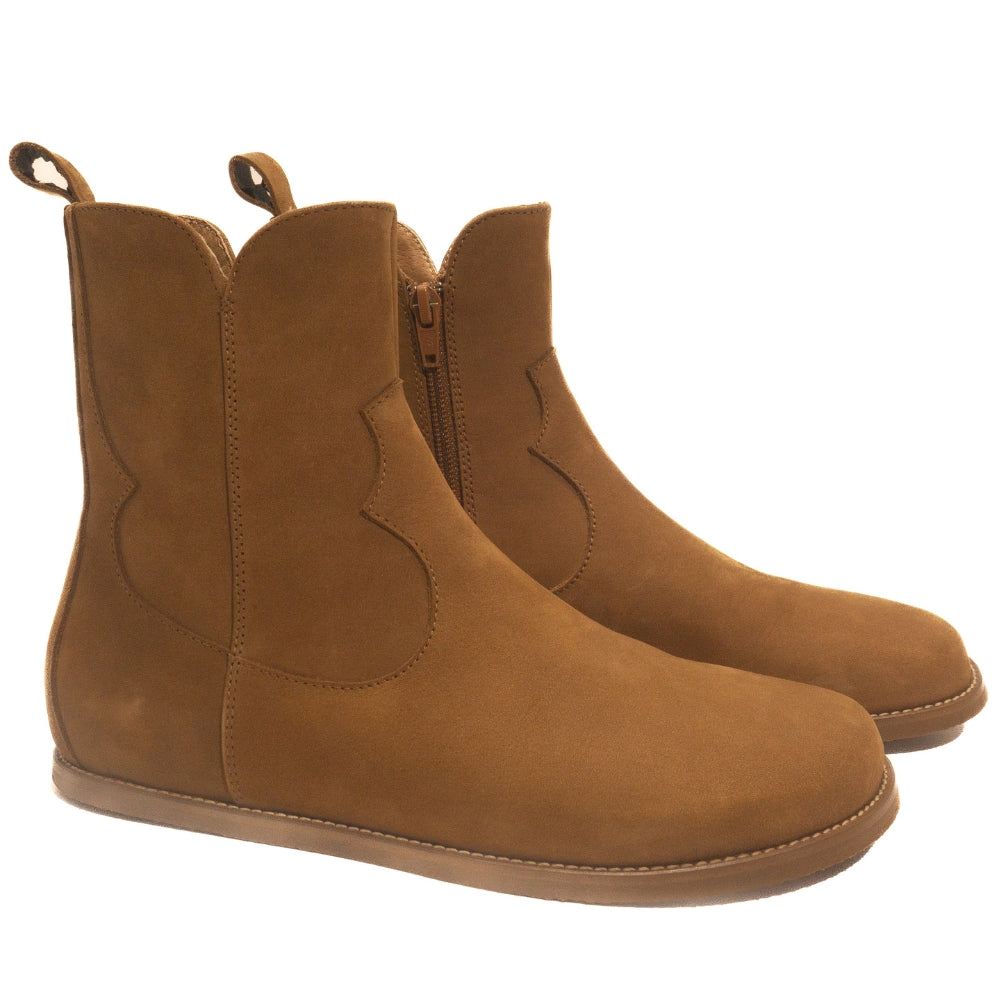 Light brown, nubuck leather western Faye boots By Anya with a western shape on both sides of the ankles, a zipper, tan rubber soles, a welt stitching design around the top of the sole, and a pull tab at the top back of the opening. Both boots are shown facing diagonally right against a white background. #color_cider