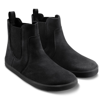 A photo of Be Lenka Entice boots made from nubuck leather and rubber soles. The boots are black in color, they are a Chelsea boot style with elastic at the sides. Both boots are shown diagonally from the front right on an white background. #color_matte-black