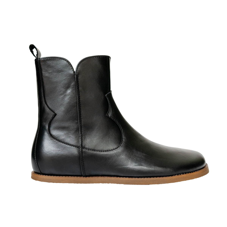 The Faye western boot By Anya, a black leather ankle boot with a side zipper, pull tab, and a light brown outsole, shown in profile against a white background. #color_black