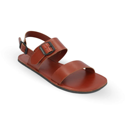Brown leather Groundies Kos Sandals with black rubber soles. One thick strap spans across the base of the toes while another goes across the arch of the foot with a big, black buckle closure. A thinner slingback strap keeps the sandals secure to the foot also with a buckle closure. Right shoe is shown facing diagonally right against a white background. #color_cognac