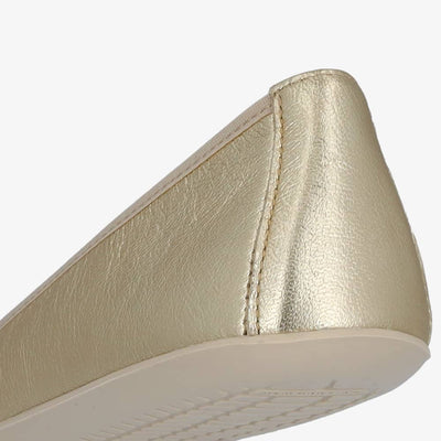 A photo of Groundies Lily Classic flats with a leather upper and white rubber true sense soles. The flats are a perforated leather in a metallic champagne color with trim around the tops. The interior of the flats is a light beige color. The right flat is shown from behind, displaying the heel of the shoe, on a white background. #color_metallic-champagne