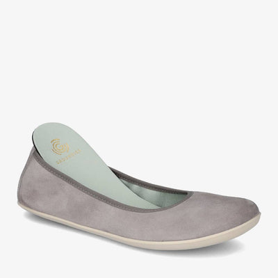 A photo of Groundies Lily Soft flats with a leather upper and cream rubber true sense soles. The flats are a nubuck in a grey color, the trim around the tops of the flats is also grey and is darker in color than the rest of the flats. The right flat is shown from the right side against a white background, with the heel of the removable insole popped out of the shoe. #color_grey