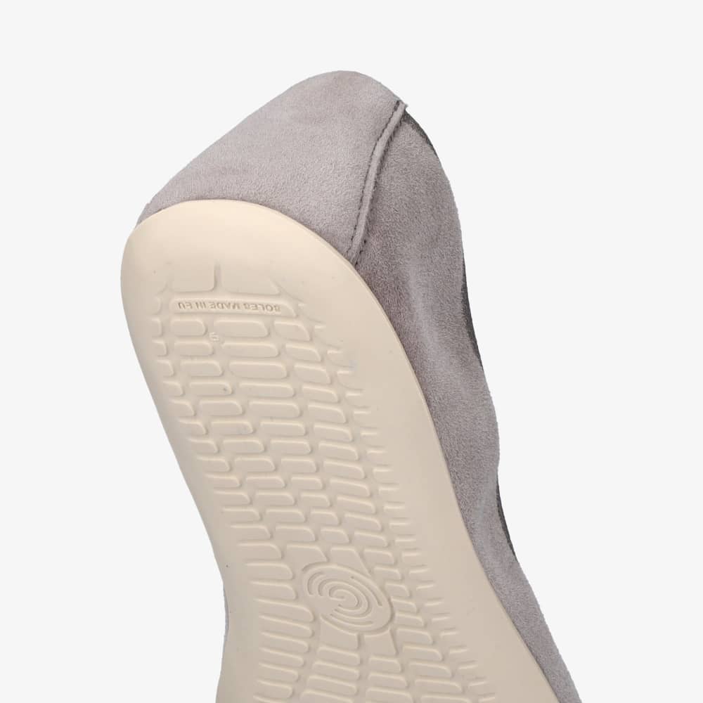 A photo of Groundies Lily Soft flats with a leather upper and cream rubber true sense soles. The flats are a nubuck in a grey color, the trim around the tops of the flats is also grey and is darker in color than the rest of the flats. The right flat is shown angled down with a view of the heel of the sole against a white background. #color_grey