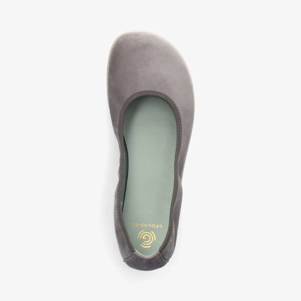 A photo of Groundies Lily Soft flats with a leather upper and cream rubber true sense soles. The flats are a nubuck in a grey color, the trim around the tops of the flats is also grey and is darker in color than the rest of the flats. The right flat is shown from above against a white background. #color_grey
