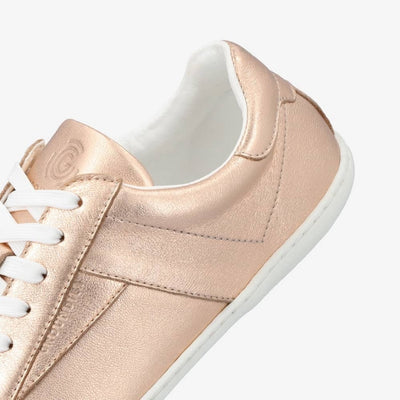 A photo of groundies melbourne shoe in metallic rose gold. Shoe is shown floating diagonally from the right side close up to the heel portion of the shoe against a white background. #color_metallic-rose