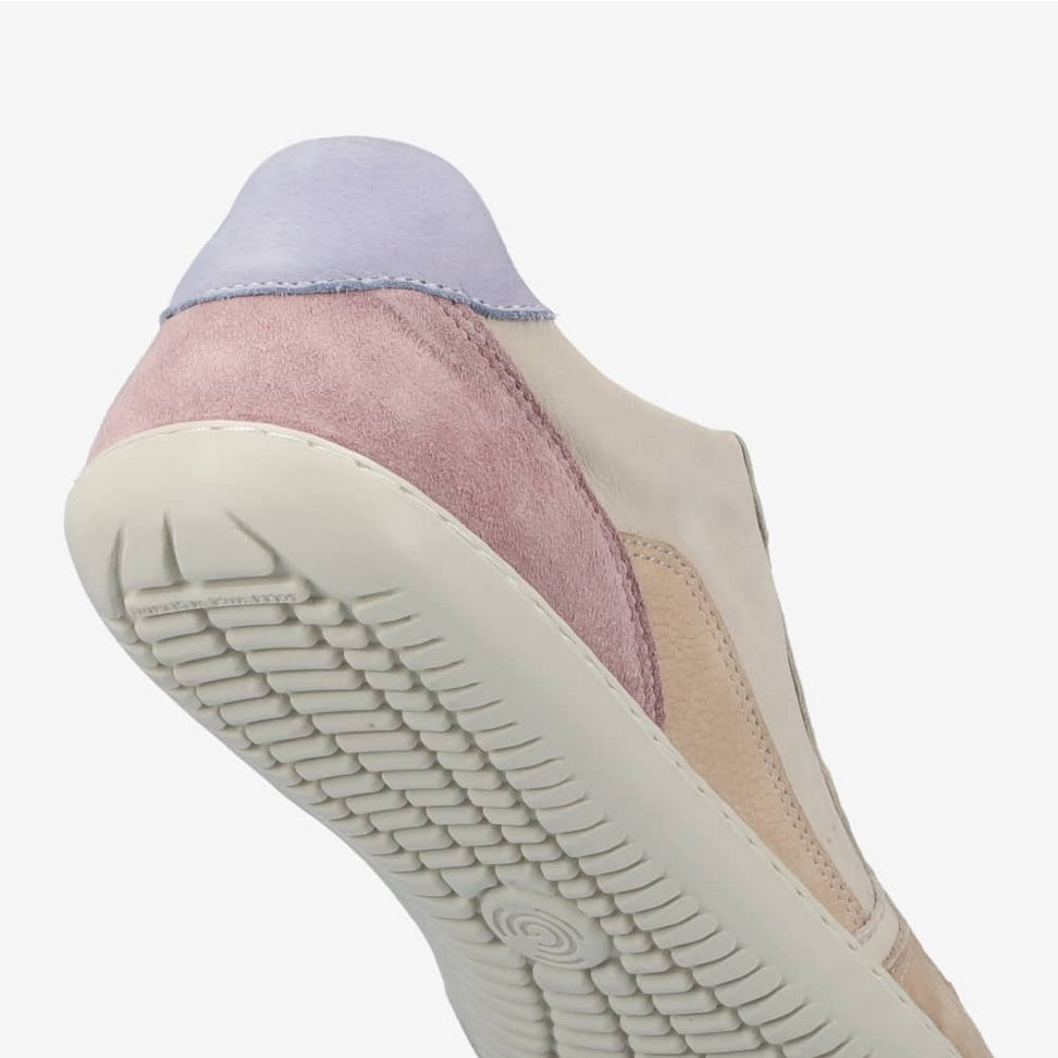 A photo of Groundies Nova GO1 Sneakers made with soft leather and white rubber soles. The sneakers have Beige, Periwinkle, and Pink color blocks. The right shoe is shown diagonally floating from the bottom right showcasing the sole against a white background in this photo. #color_beige-lavender-pink
