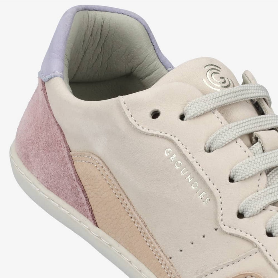 A photo of Groundies Nova GO1 Sneakers made with soft leather and white rubber soles. The sneakers have Beige, Periwinkle, and Pink color blocks. The right shoe is shown from the right ankle showcasing the leather color blocks against a white background in this photo. #color_beige-lavender-pink
